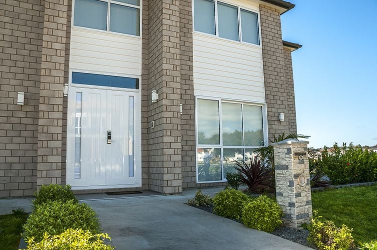Exterior of a two-storey brick house with off-white trim and a white front door.