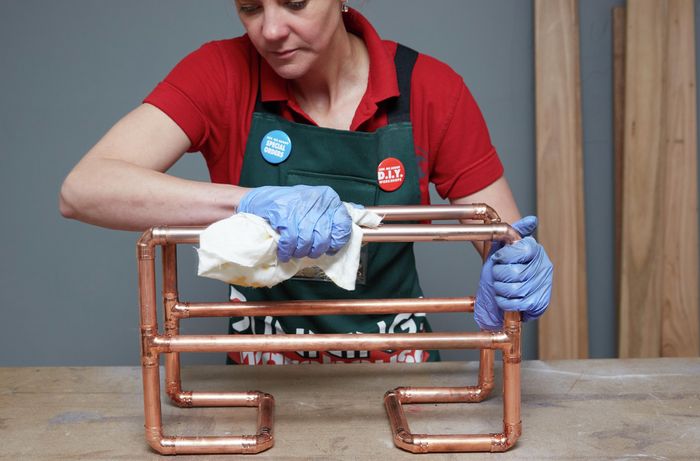 Person polishing copper magazine rack