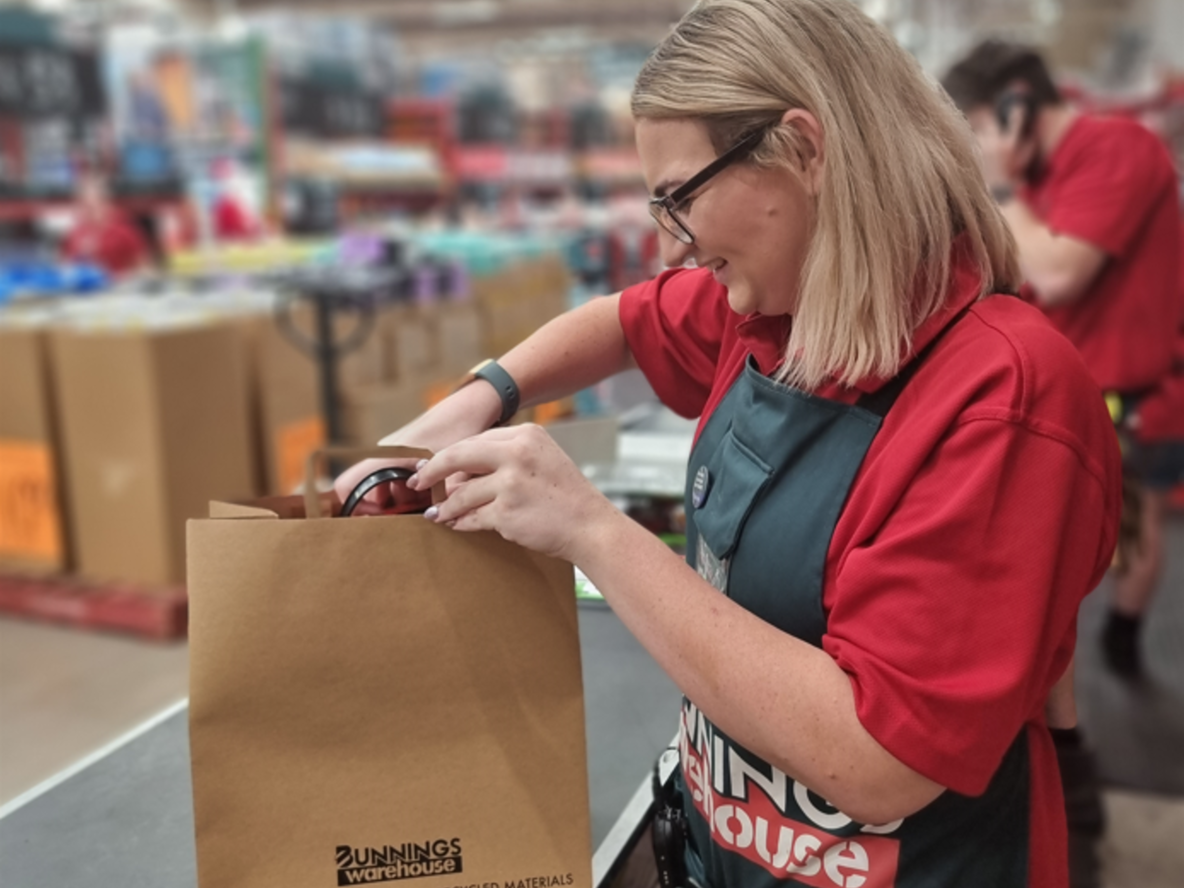 Bunnings team member in store packing product into brown paper bag