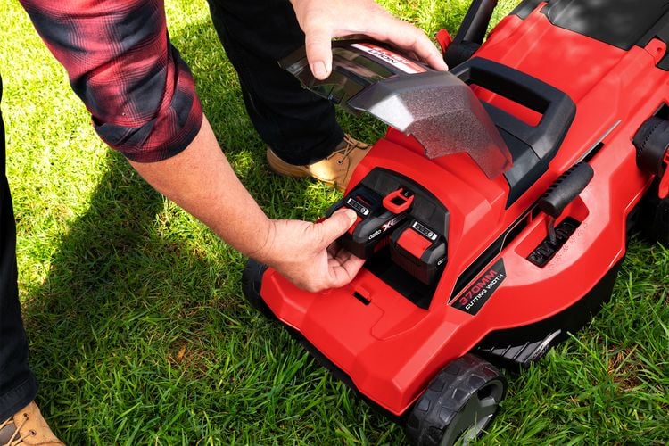 Person replacing battery in lawnmower