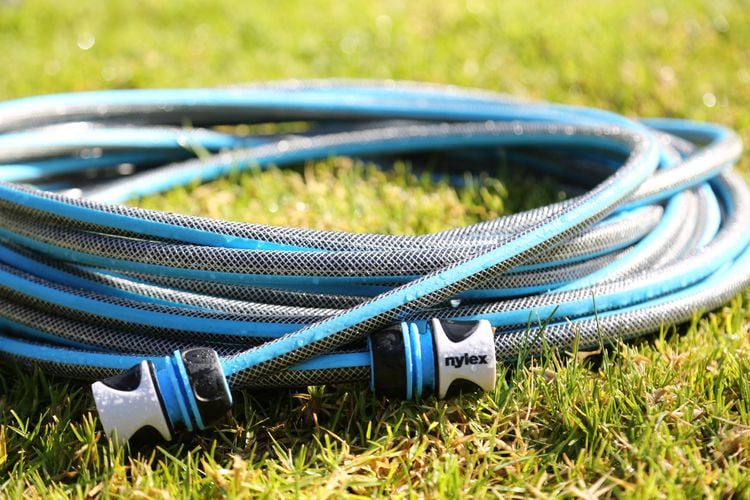 Close up of a blue Nylex garden hose with signature branded blue and white tap fittings on end