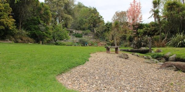 Outdoor area with path grade pebbles, trees and bench 