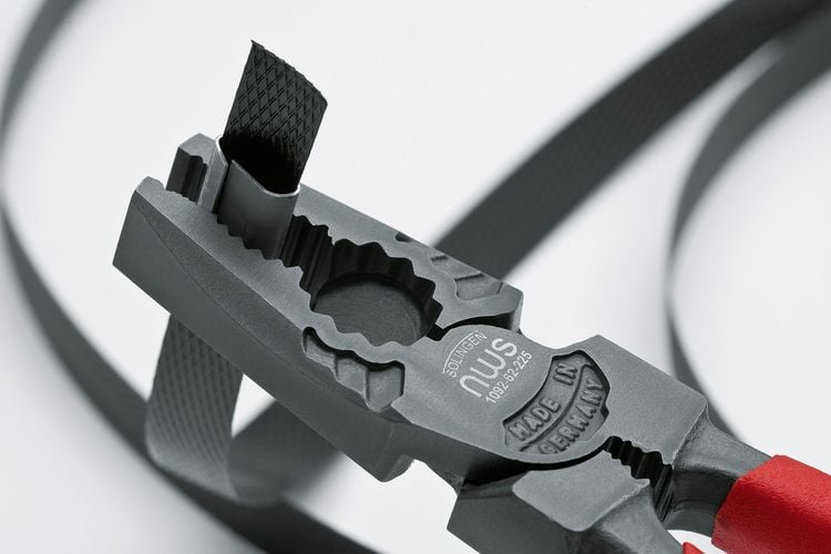 Pliers clamping piece of metal to strapping