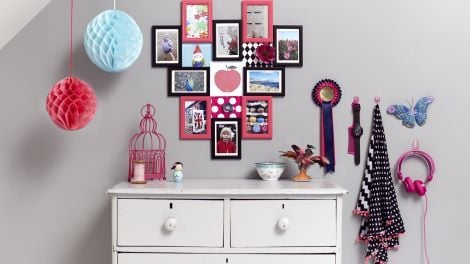 Pictures hung on wall above chest of drawers