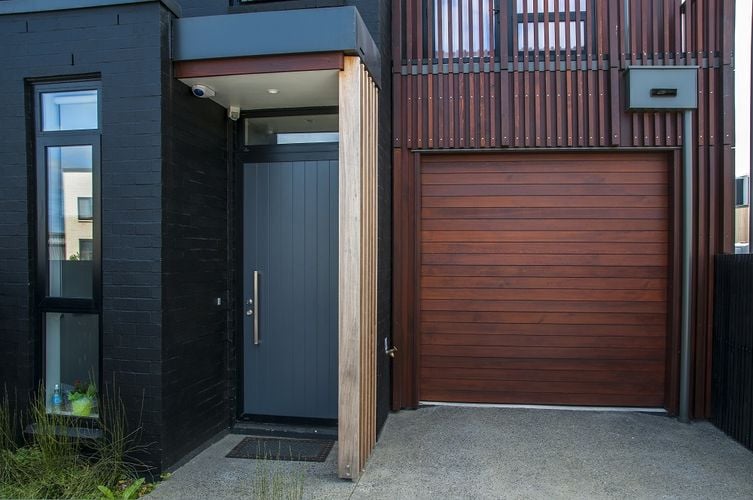 Front entryway with grey wooden door with large handle
