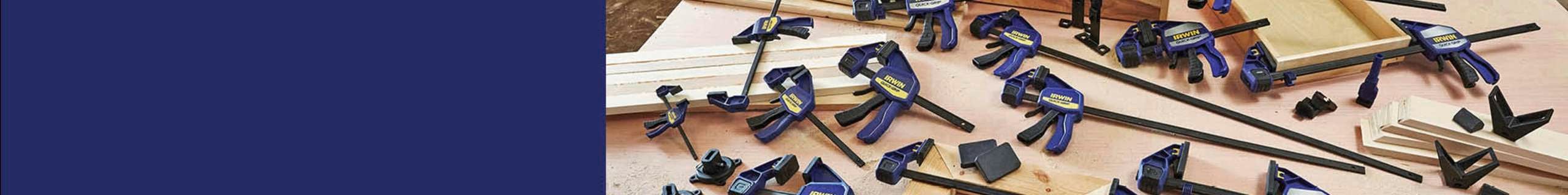 Multiple Irwin quick-grip clamps sprawled across a workbench and surrounded with timber