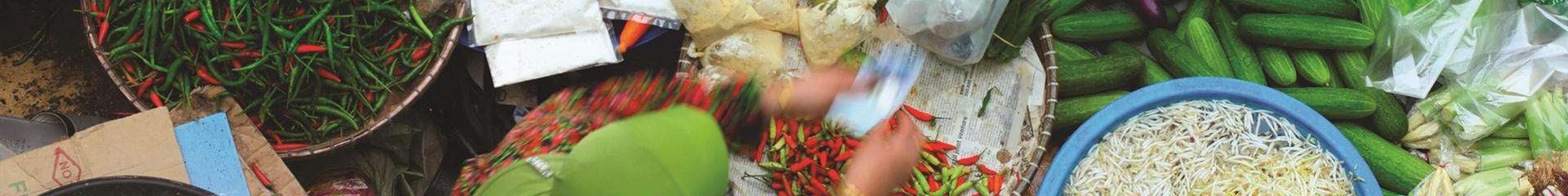 Top view of a person sorting through various vegetables including chilis