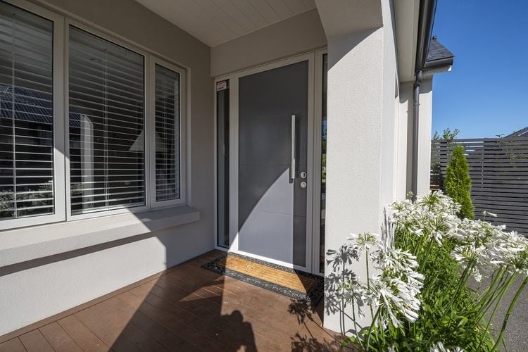 Exterior of a modern townhouse painted pale grey with a dark grey front door.
