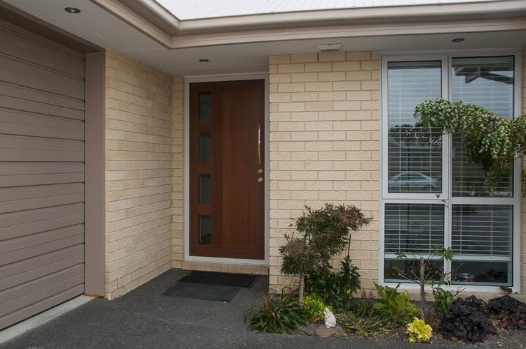Front entryway to home with wooden garage door and front door