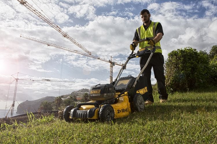 Man mowing lawn with powered lawnmower