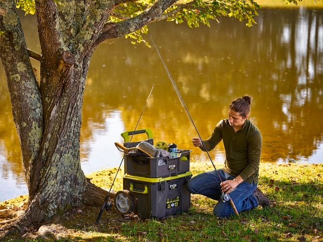 A person fishing with items stored in an open crate.