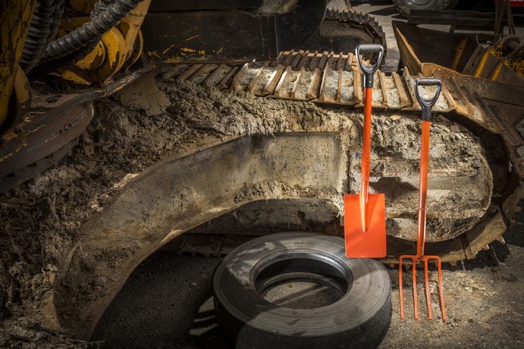 Shovel and fork leant against an excavator