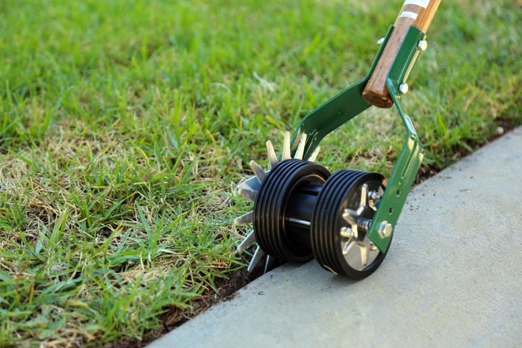 Person refining turf edge with an edging tool