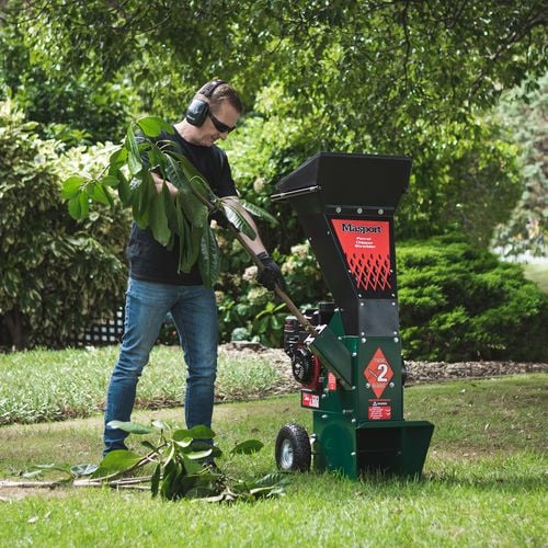 Person feeding tree branch into wood chipper