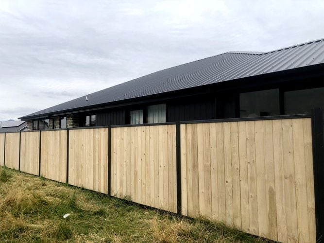 Tall laminated timber fence between house and park