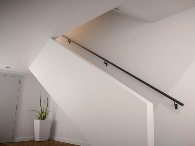 A modern white stairwell with long black railing