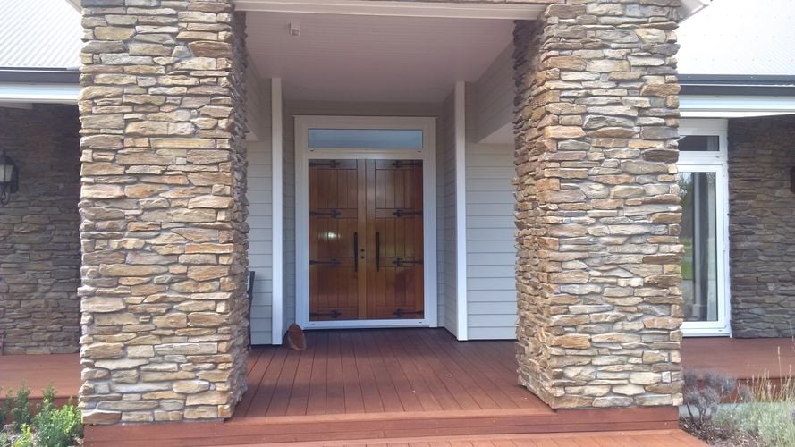 Front entryway to home with stacked stone facade and double wooden door
