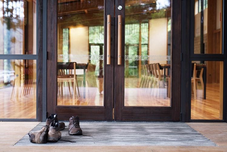 Double wooden door at entry to building with shoes left by the door