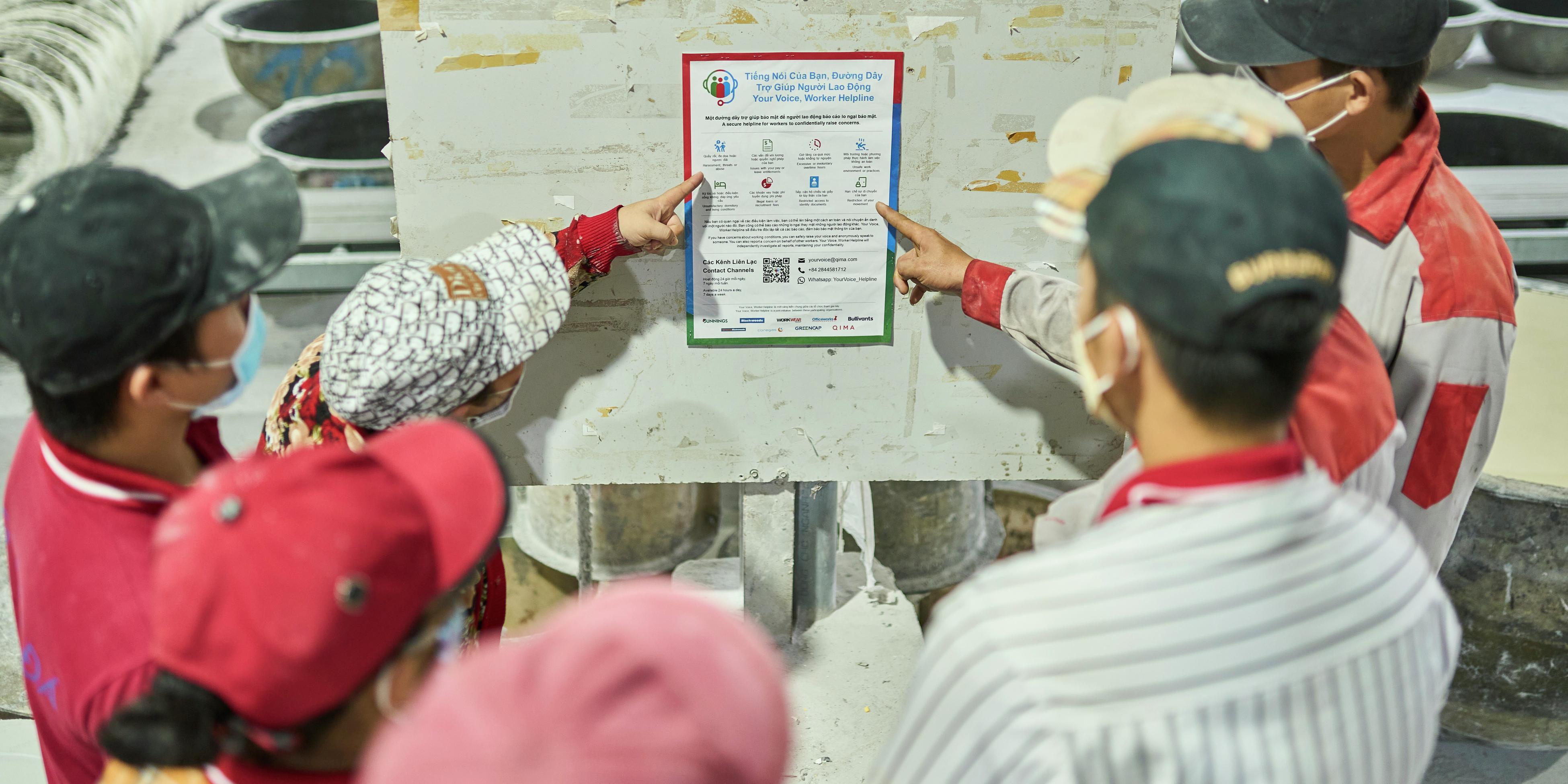 Factory workers looking at a safety poster 