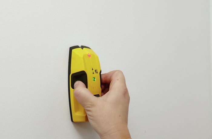 A stud finder used to find the stud in a white wall