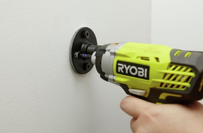 Flanges being screwed into a wall with a power drill
