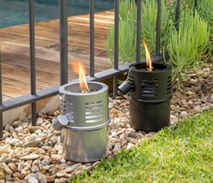 Two insect repellent candles in a garden by a pool