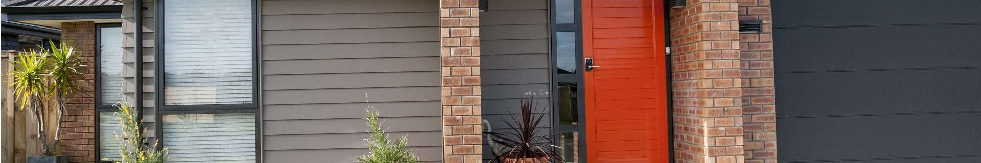 Exterior of the front of a home with an orange Strata Front Doors door