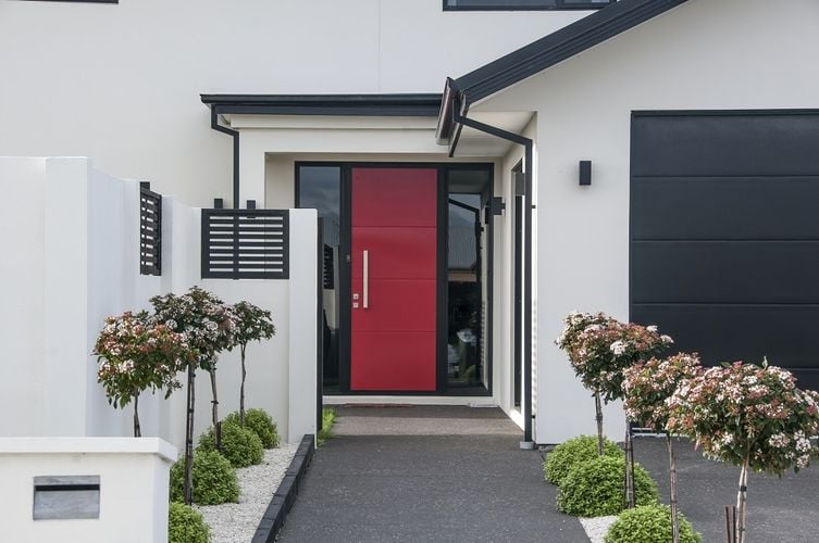 Exterior of a modern townhouse painted off-white with a red front door.