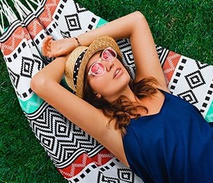 A woman in a straw hat and sunglasses reclining in a hammock