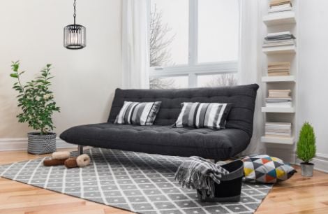 Black couch on a patterned rug next to floating book shelving
