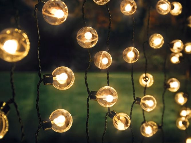 Two girls holding a glass jar full of fairy lights