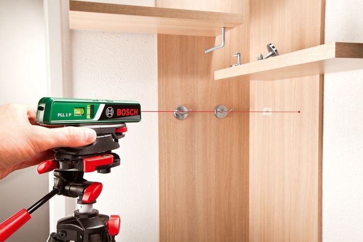 Person using laser level to level hand towel hooks in bathroom