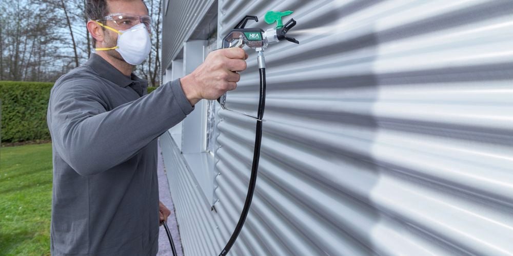 Wagner
  Control Pro Hybrid Gun with HEA tip spraying outdoor corrugated metal with
  light gray paint