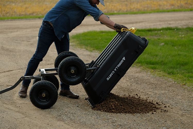 Person tipping cart full of soil onto ground