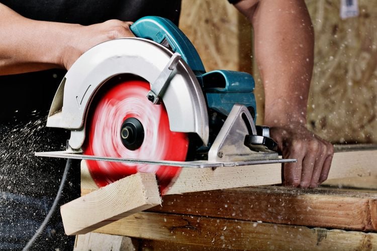 Person using circular saw to cut timber