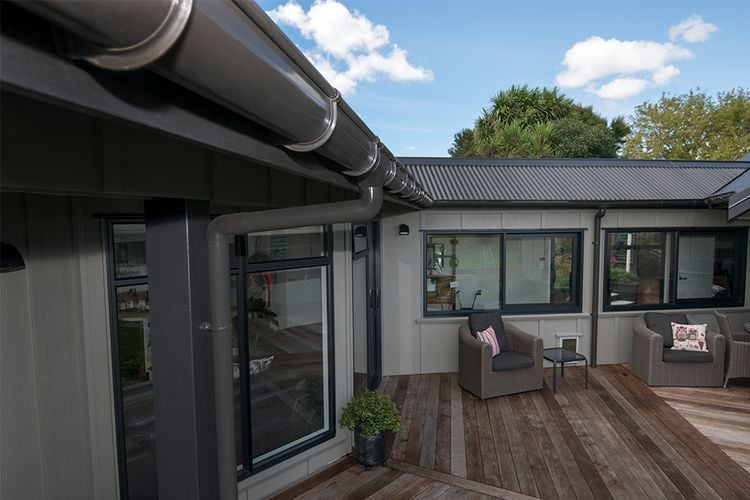 House exterior with timber decking and drainage pipe