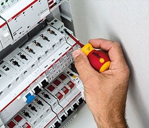 using a small red and yellow wiha precision screwdriver to adjust a circuit breaker