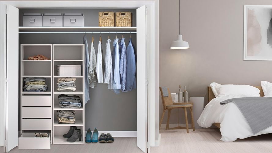 Organized built in wardrobe in bedroom with bed and chair.
