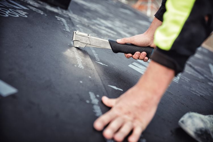 Person stapling flooring to ground