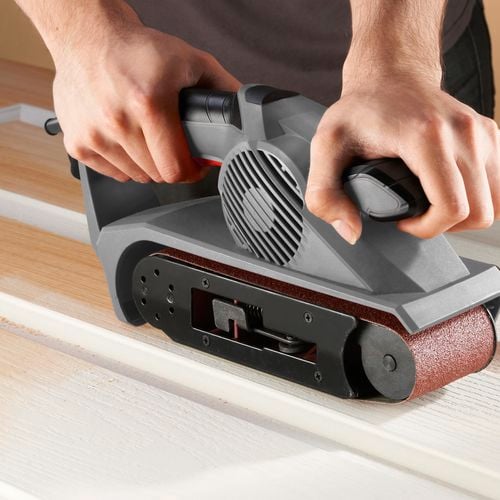 Close up of an Ozito belt sander - sanding paint off a wooden surface