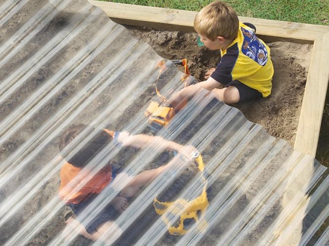 Clear suntuf protection on top of sandpit with kids playing