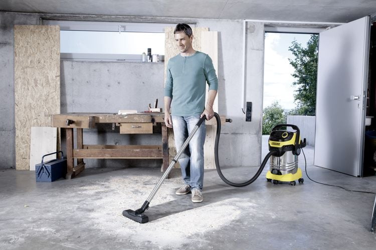 Man using vacuum to clean up saw dust in garage