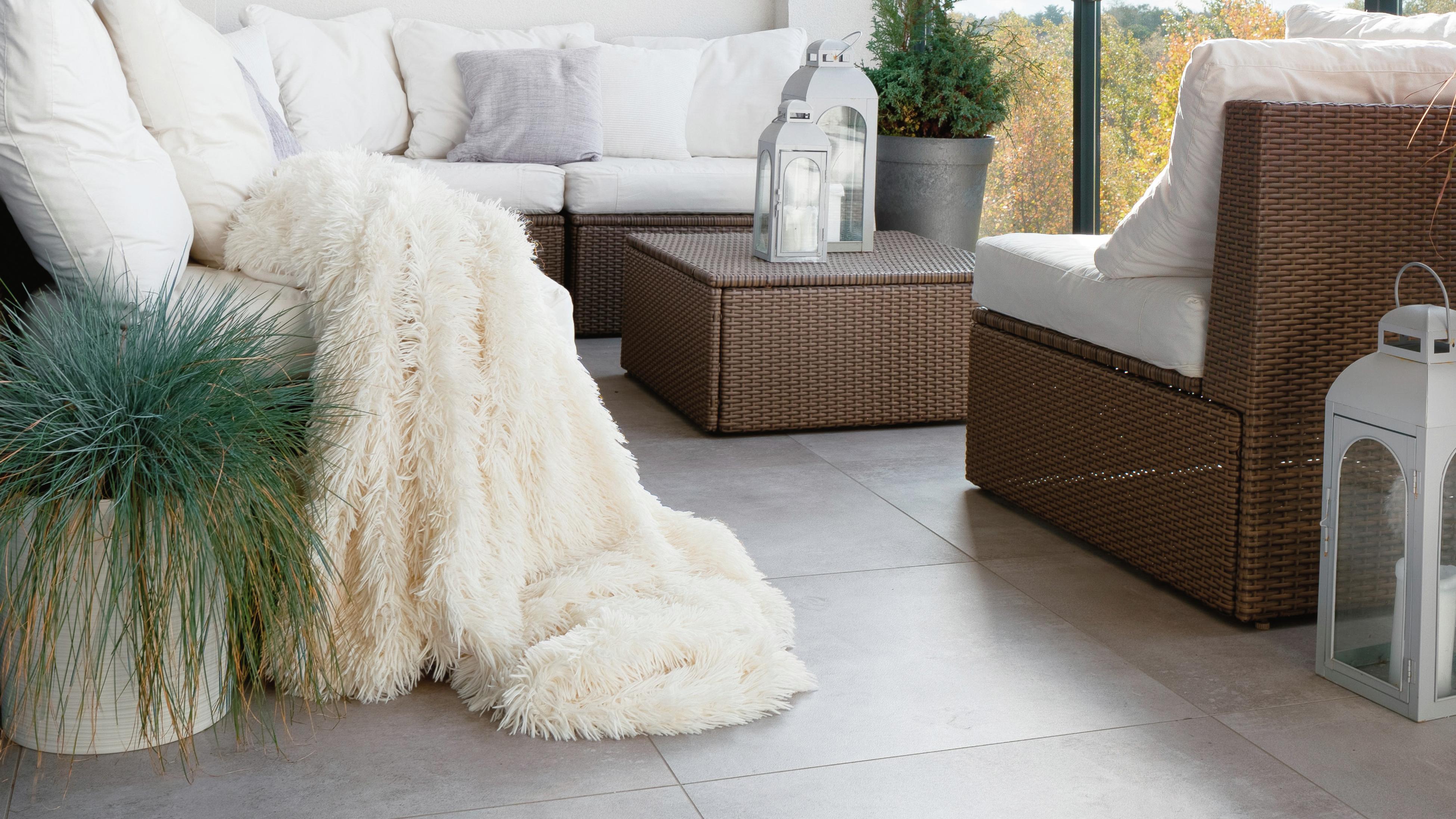 Elegant decorated balcony with wicker furniture, white pillows and decorative plant