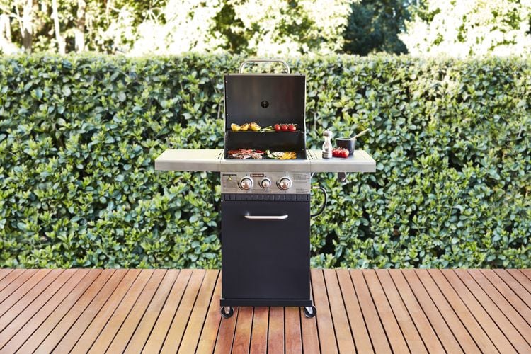 Small barbecue sitting on a timber deck cooking vegetables