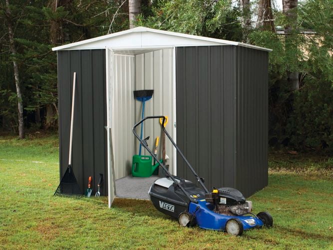 An opened shed with gardening tools and a lawn mower at the front.