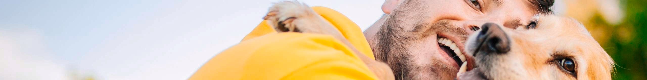 A man cuddling a dog close up.