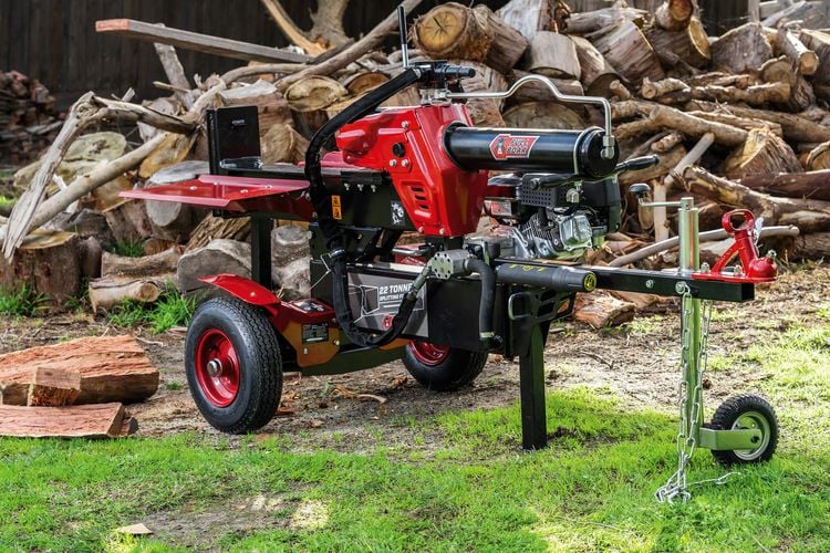 Motorised wood splitter in front of wood pile