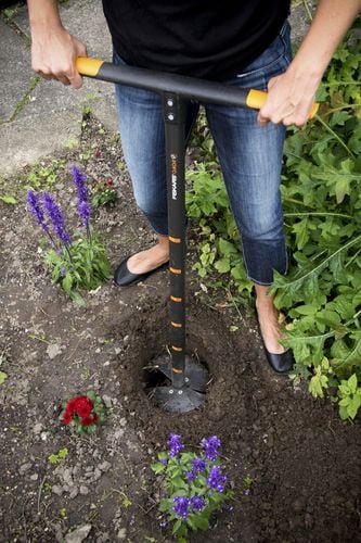 Person making a hole in garden using hole digging tool