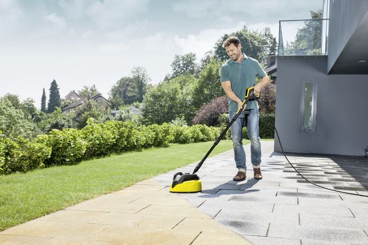 Person using high pressure hose to clean outdoor tiles