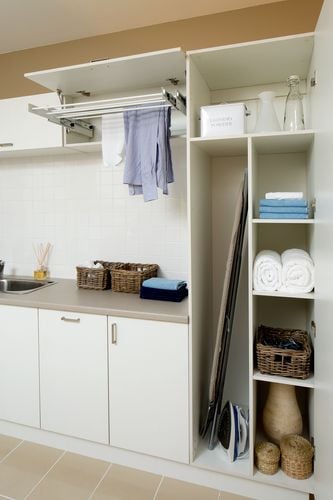 Laundry with neat cupboards containing a drying rack, ironing board, iron and towels